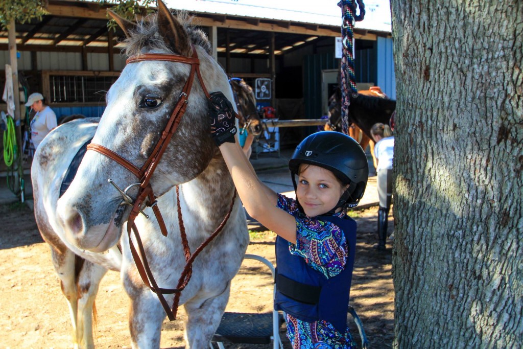 Portia tacking up Appaloosa horse Freckles for a group riding lesson